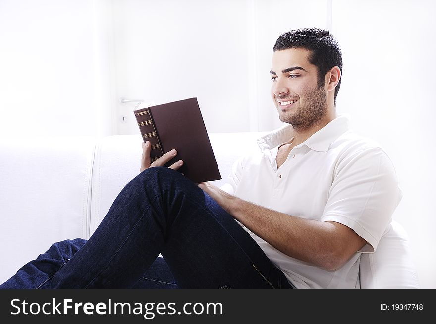 Young man reading book in home interior on white background