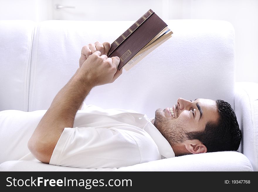 Young man reading book in home interior on white background