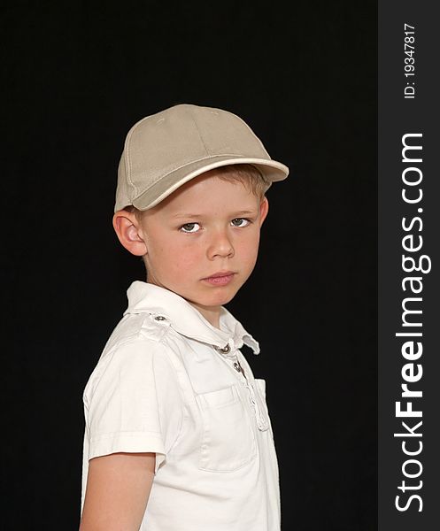 Adorable young boy in a baseball hat isolated on a black background