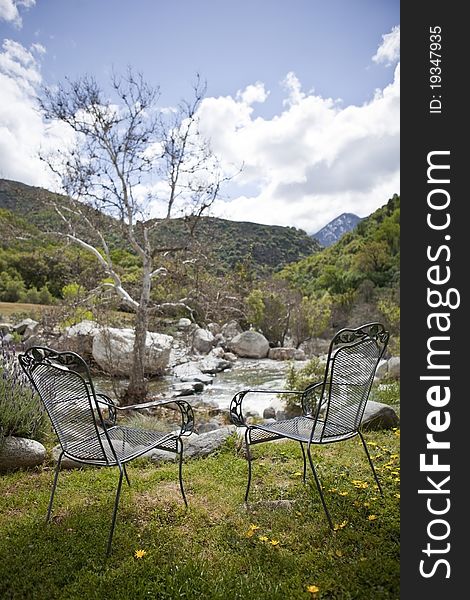 Two chairs near mountain quick spring river at sunny day