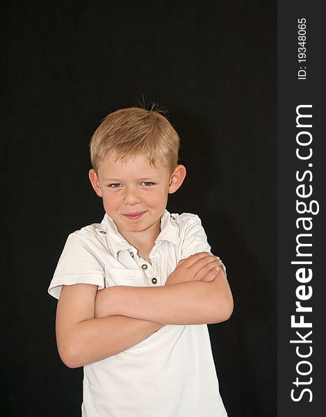 Adorable young boy with arms crossed isolated on a black background. Adorable young boy with arms crossed isolated on a black background