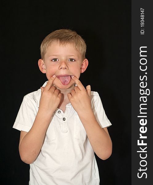 Adorable young boy pulling a funny face isolated on a black background
