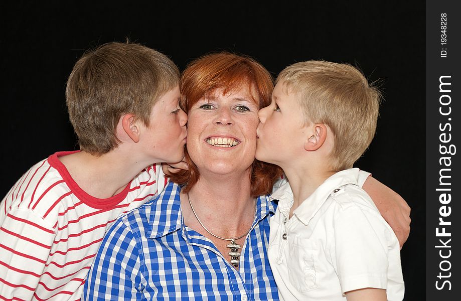 Mother and two young sons kissing