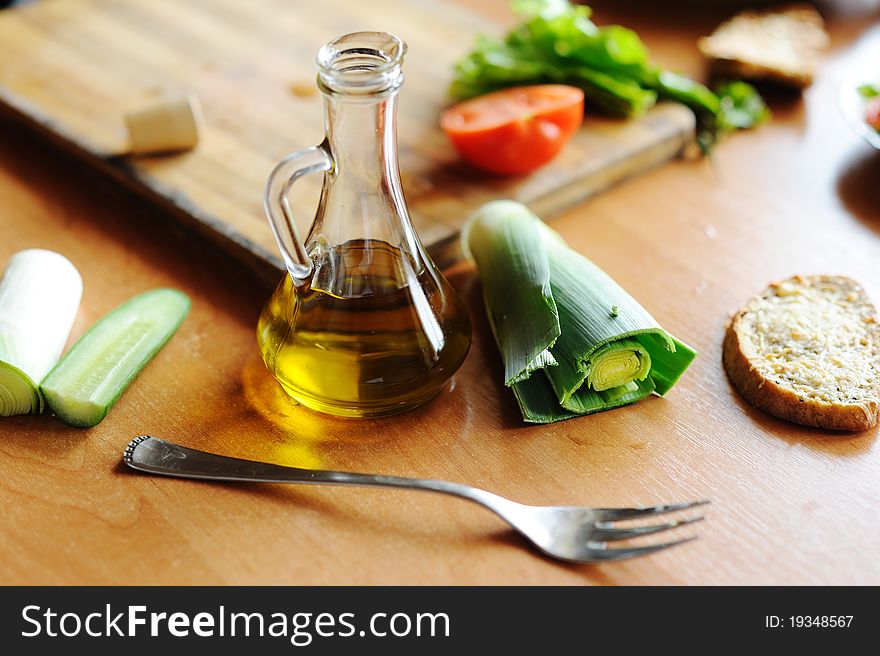 A bottle of olive oil and vegetables on the table. A bottle of olive oil and vegetables on the table