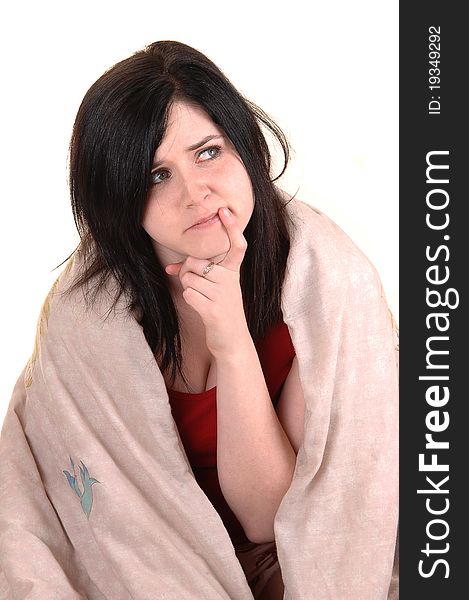 A young girl sitting on the floor covert in a blanket holding her finger to her mouths and thinking hard, for white background. A young girl sitting on the floor covert in a blanket holding her finger to her mouths and thinking hard, for white background.