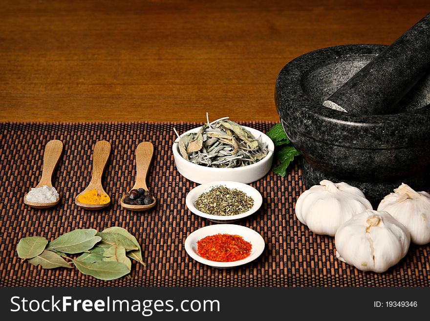 Different spices with wooden spoons and mortar on wooden table