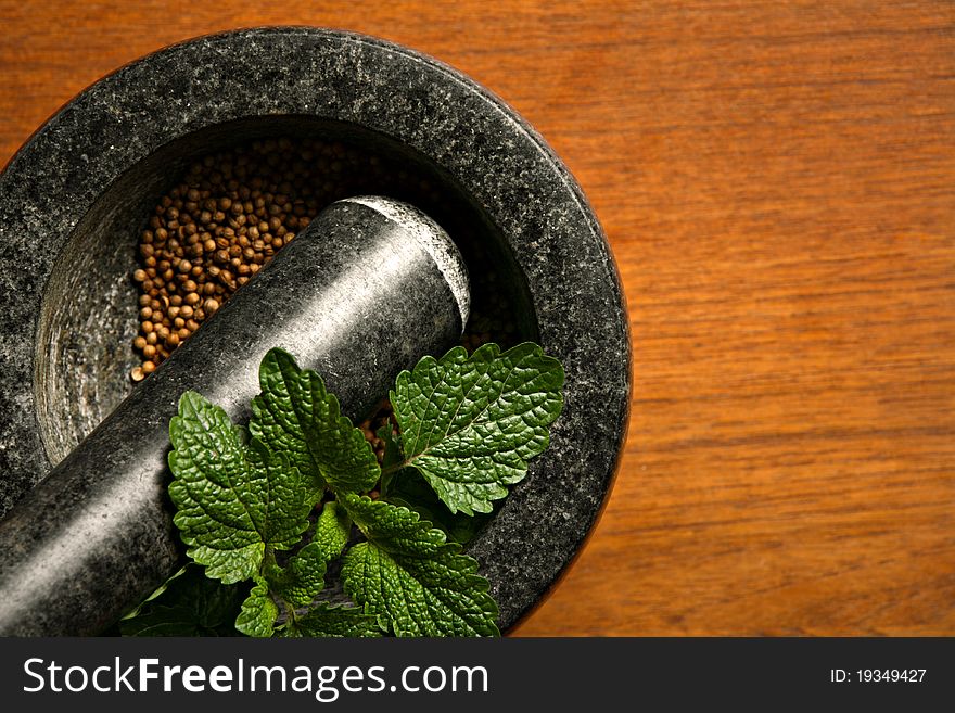 Mortar with coriander and mint on wooden table