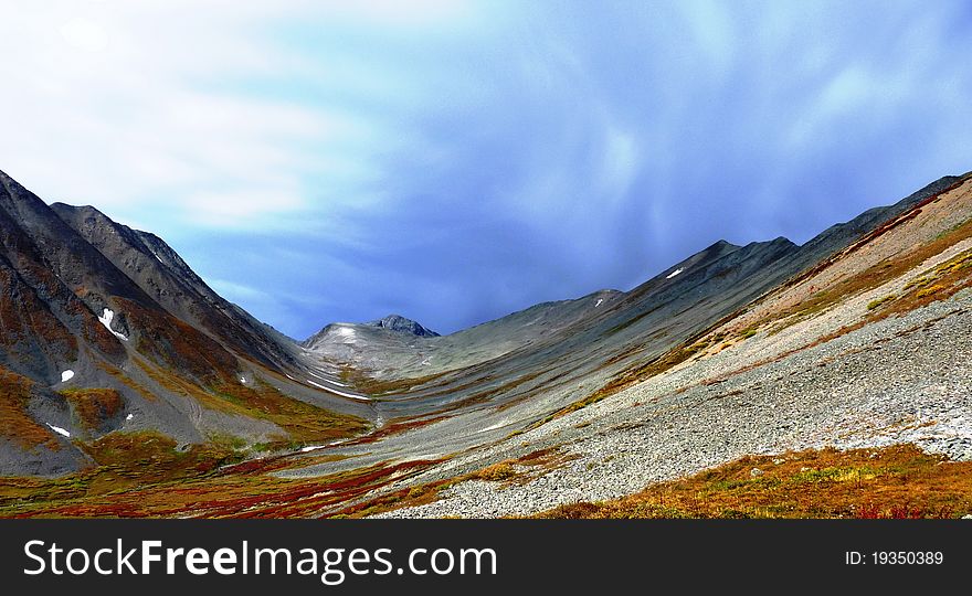 The uppers of the stony lifeless mountain valley in the background of the approaching bad weather. The uppers of the stony lifeless mountain valley in the background of the approaching bad weather