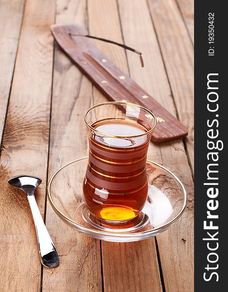 Turkish apple tea in traditional glass and plate on wooden background