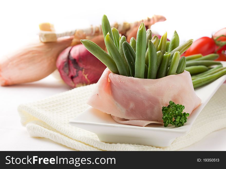 Photo of french beans with wrapped ham on white background