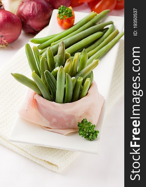 Photo of french beans with wrapped ham on white background