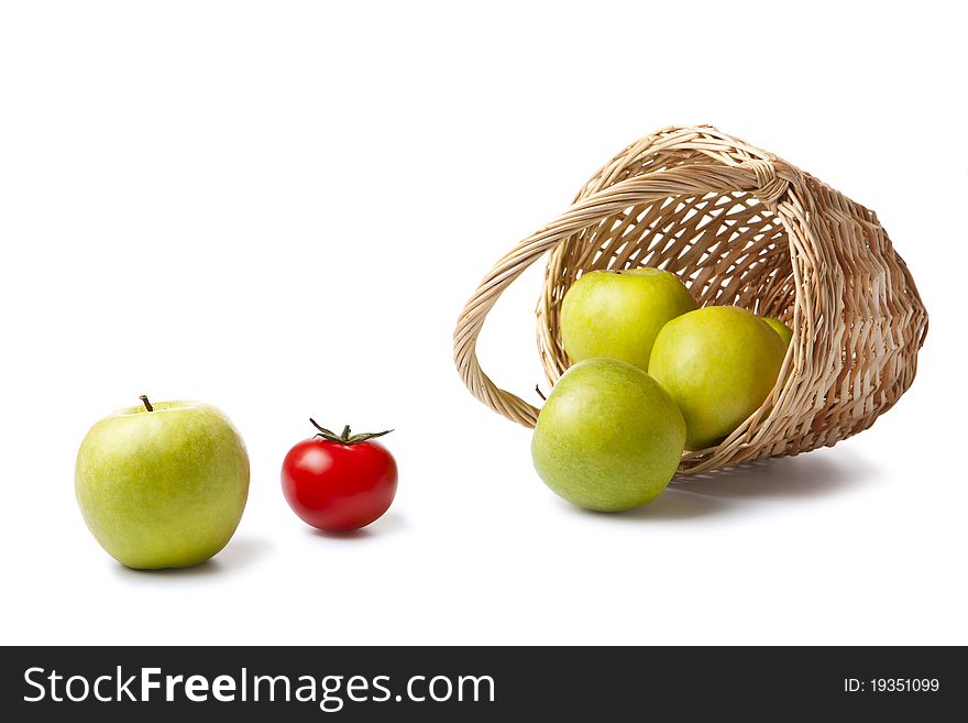 Green apples and the basket and re� tomato on white. Green apples and the basket and re� tomato on white