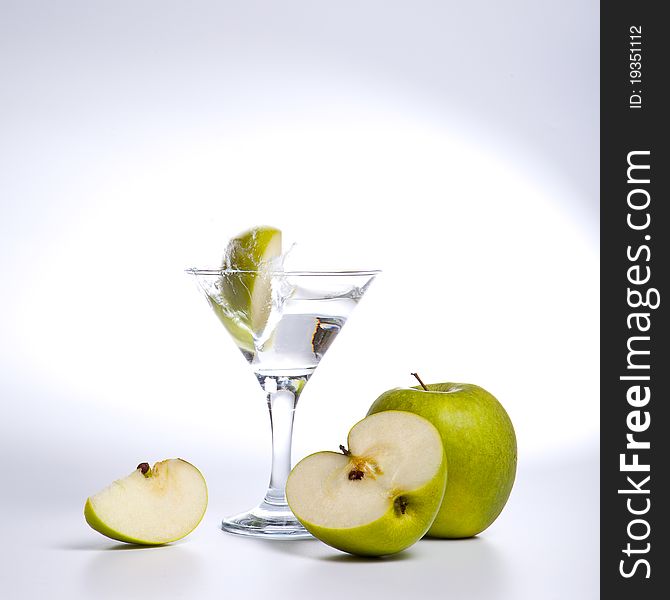 Apple cocktail splashing on a glass on white background. Apple cocktail splashing on a glass on white background