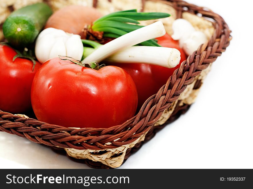 Tomatoes, cucumbers, green onions, garlic in a wicker basket isolated on white background. Tomatoes, cucumbers, green onions, garlic in a wicker basket isolated on white background..