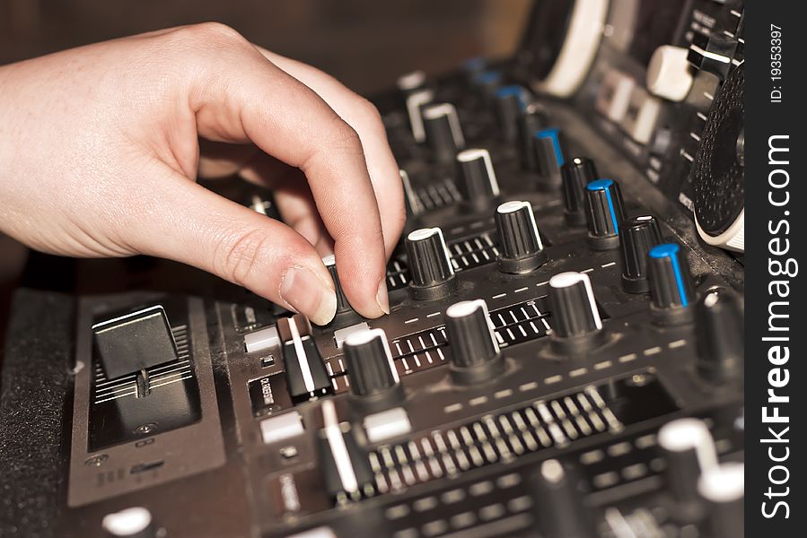 A close up of a DJ using a generic audio mixer in a nightclub. A close up of a DJ using a generic audio mixer in a nightclub.