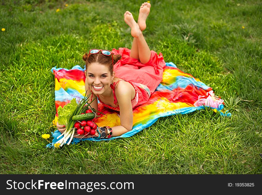 Beautiful happy woman lying on green grass with colourful vegetables. Beautiful happy woman lying on green grass with colourful vegetables