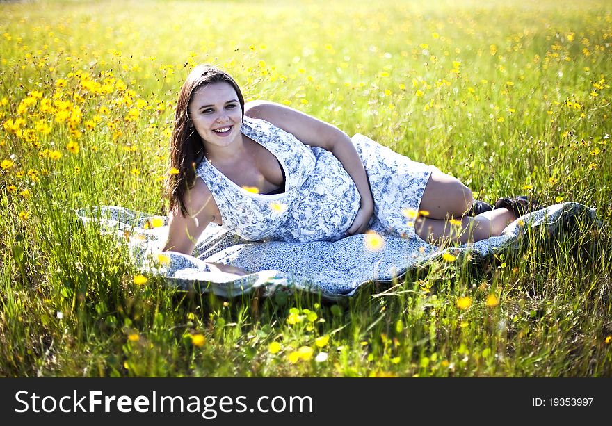 Happy, healthy pregnant woman in a field of yellow flowers touching her belly. Happy, healthy pregnant woman in a field of yellow flowers touching her belly.
