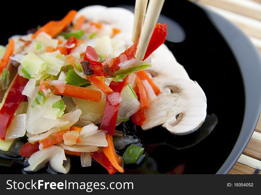 Chinese vegetables with chopsticks on a black plate. Chinese vegetables with chopsticks on a black plate