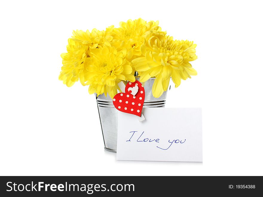 Yellow chrysanthemums in a bucket with chrysanthemums next card with the text I love you and a pin with a red heart. Isolated. Yellow chrysanthemums in a bucket with chrysanthemums next card with the text I love you and a pin with a red heart. Isolated