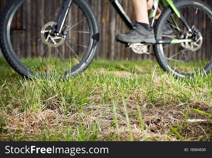 Mountain biker riding a bike in backcountry environment, blurred biker and focus on grass. Mountain biker riding a bike in backcountry environment, blurred biker and focus on grass