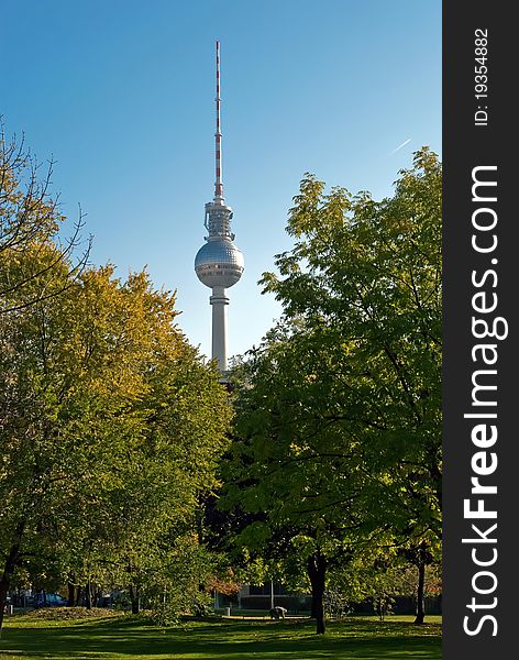 The Berlin television tower stands between green trees. The Berlin television tower stands between green trees