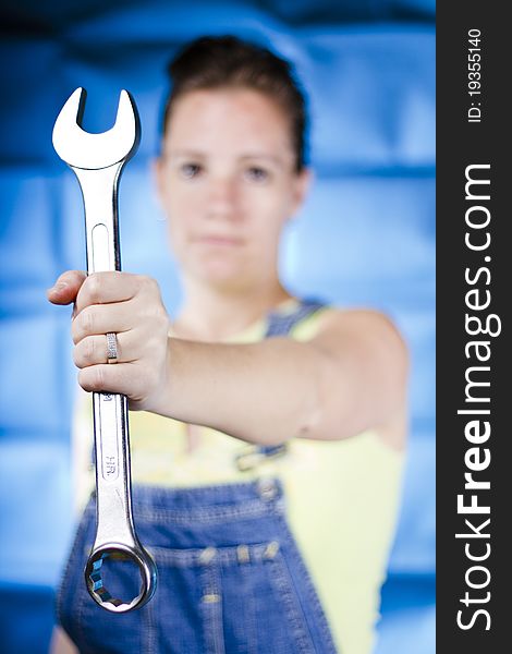 Woman holding wrench on blue background