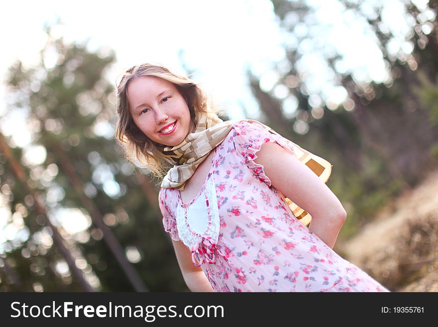 Sweet woman in beautiful dress is standing in a sunshine against spring forest. Sweet woman in beautiful dress is standing in a sunshine against spring forest