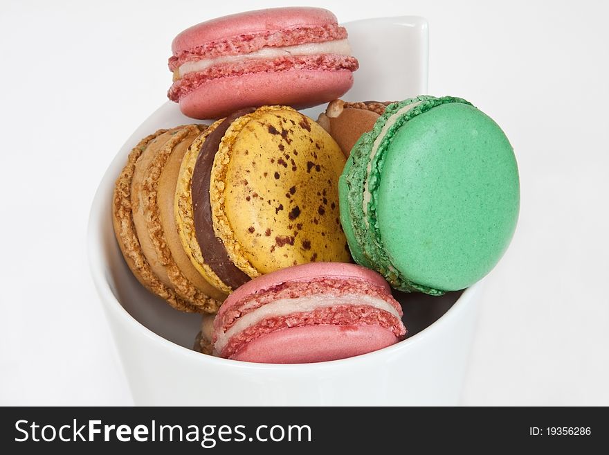 A selection of colourful macaroons in a cone-shaped white ceramic dish. A selection of colourful macaroons in a cone-shaped white ceramic dish