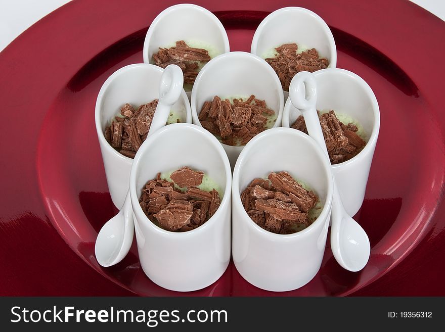 Small white pots containing lime & chocolate mousse on a red charger. Small white pots containing lime & chocolate mousse on a red charger