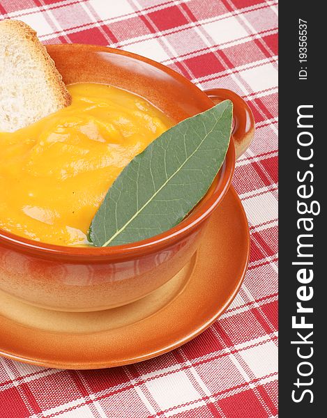 Cream of squash soup in a casserole pot with a bay leaf and toasted bread
