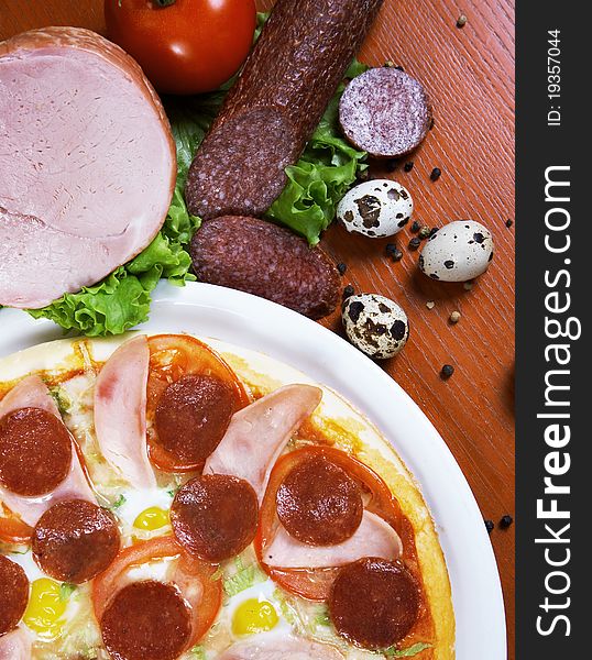Pizza with salami, ham, edd and tomato, on a table