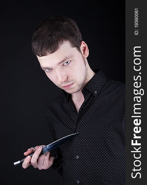 Portrait of depressive man with knife in black cloth. Portrait of depressive man with knife in black cloth