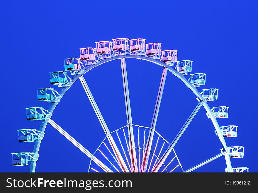 A big colorful ferris wheel and blue sky.