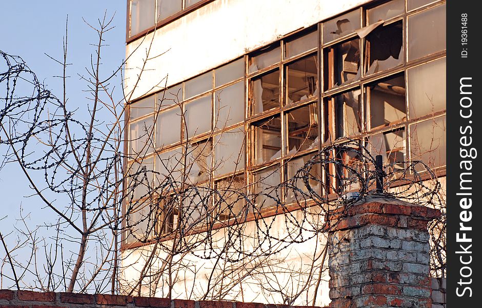 Ruined industrial building with broken windows and barbed wire