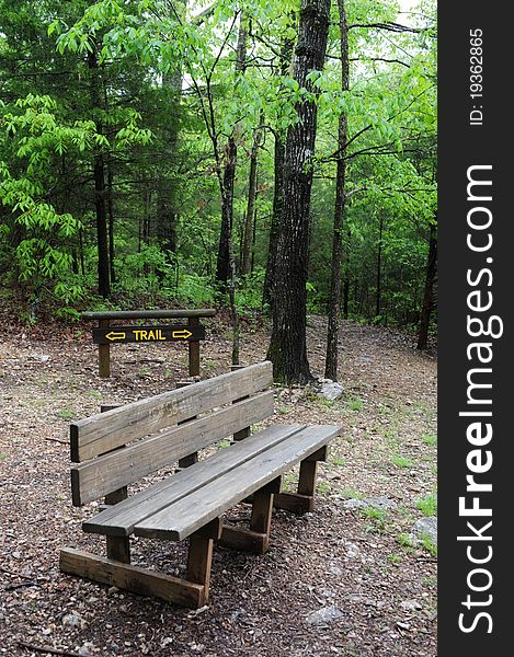 Hiking trail sign in the woods with rustic bench