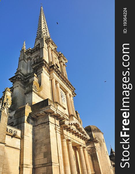 A French cathedral and its tall bell tower under a blue sky