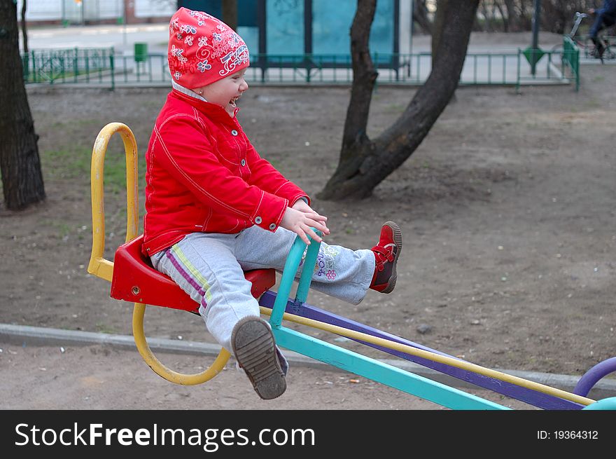 Pretty little girl play on the playground seesaw (teeter-totter). Pretty little girl play on the playground seesaw (teeter-totter).