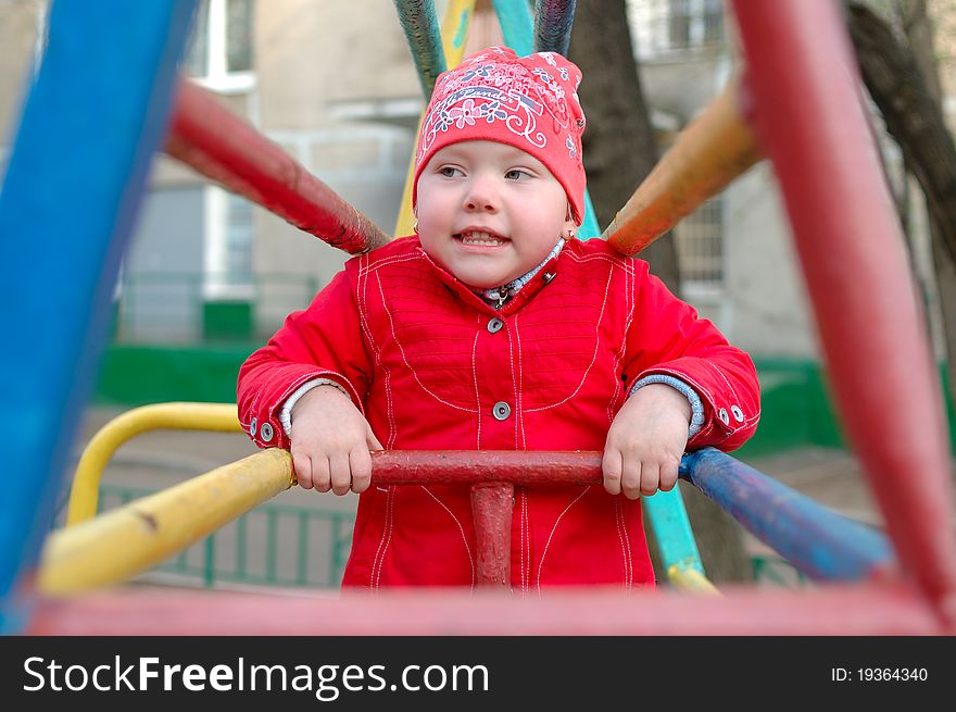 Pretty little girl play on the playground metal monkey bars. Pretty little girl play on the playground metal monkey bars.