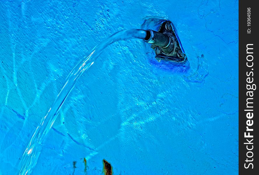 A very blue water fountain with sun light reflections