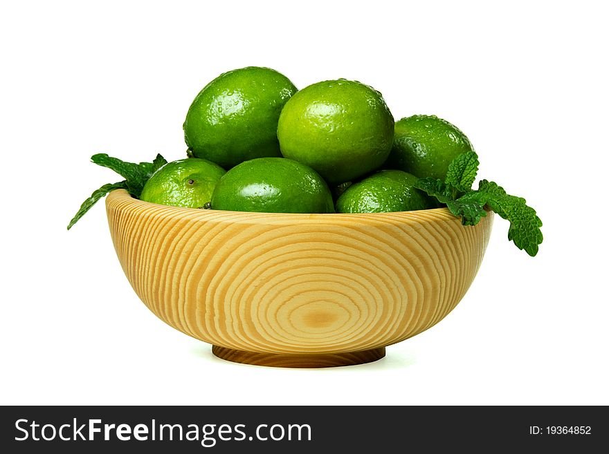 Fresh limes in wooden bowl, isolated on white