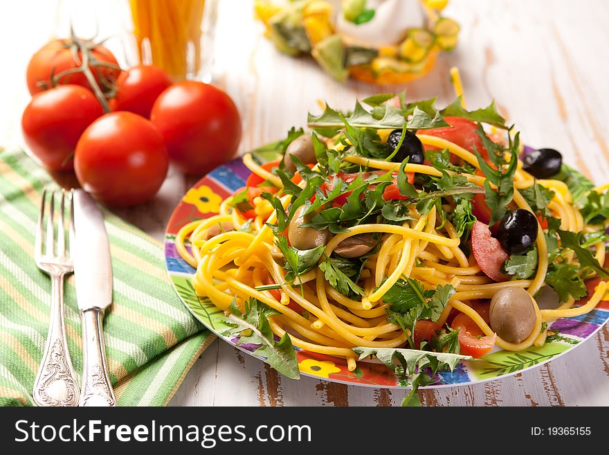Plate of spaghetti with olives, tomatoes and herbs