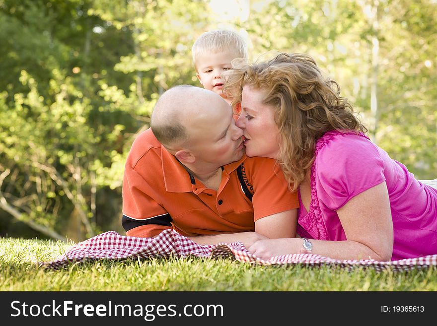 Affectionate Couple Kiss As Cute Son Looks On