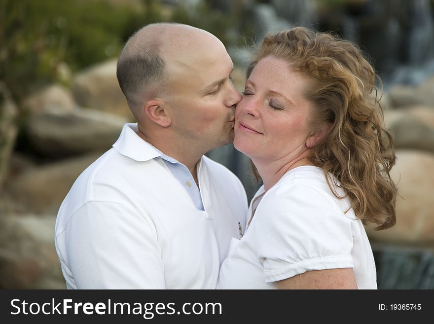Happy, Attractive, Affectionate Couple Kiss on Cheek in the Park. Happy, Attractive, Affectionate Couple Kiss on Cheek in the Park.