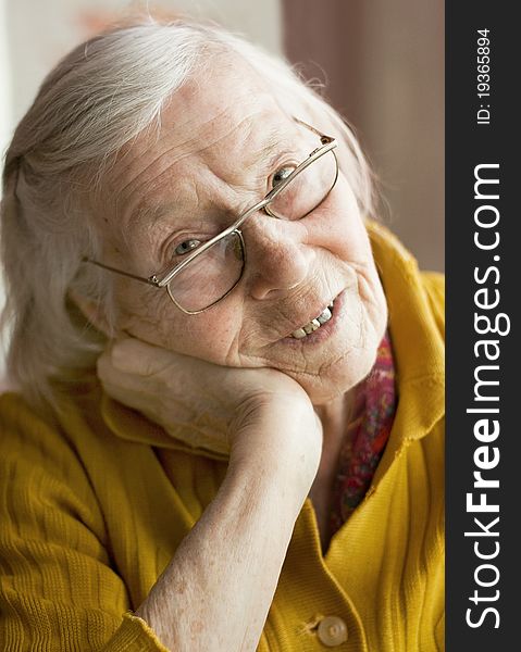 An elderly woman reads a newspaper with glasses. An elderly woman reads a newspaper with glasses