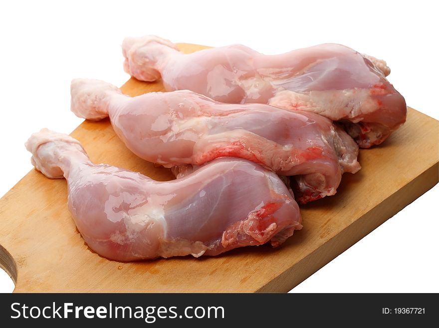 Three raw chicken legs on a cutting board