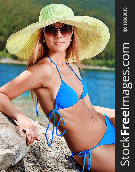 Beautiful young woman in bikini posing on a sea beach.