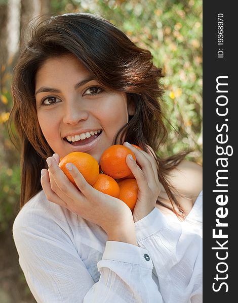 Street portrait of a smiling young Spanish girl with a tangerine