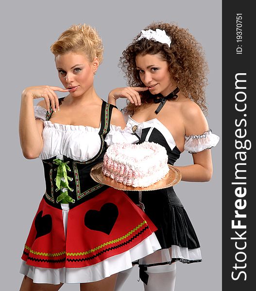 Two pretty waitress with a large cake with cream
