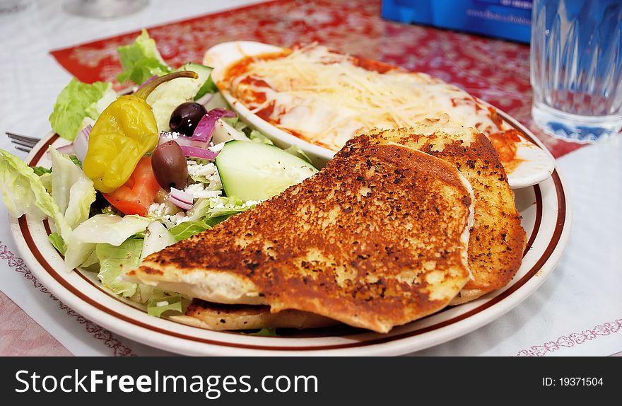 Greek salad on a white plate with bread and magaterenian food in restaurant. Traditional Greece food. Greek salad on a white plate with bread and magaterenian food in restaurant. Traditional Greece food.