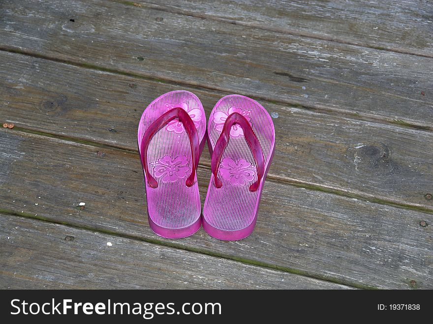 A pair of pink sandals by the pool deck